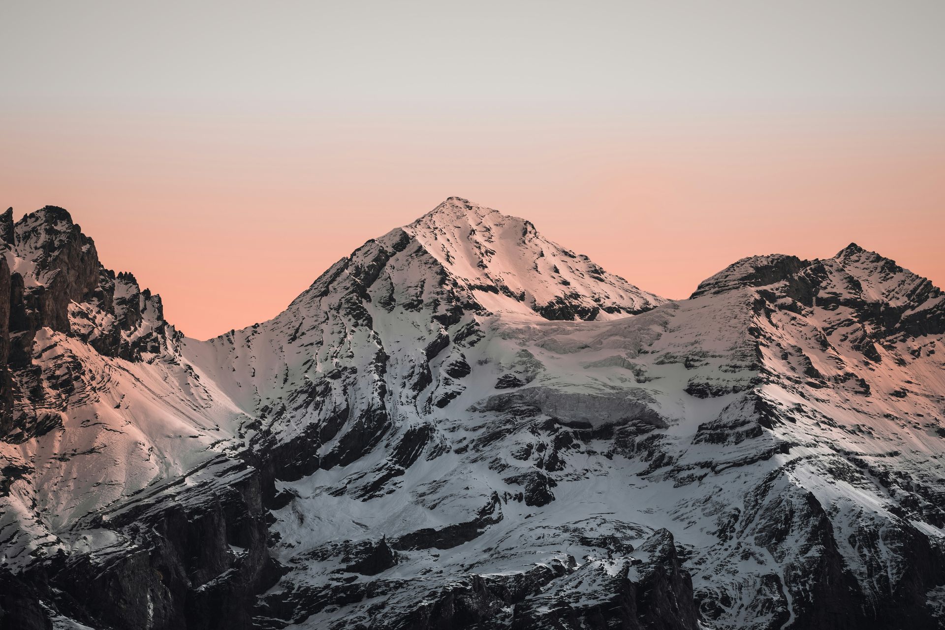 Sommet enneigé au coucher du soleil, ciel rose-orangé